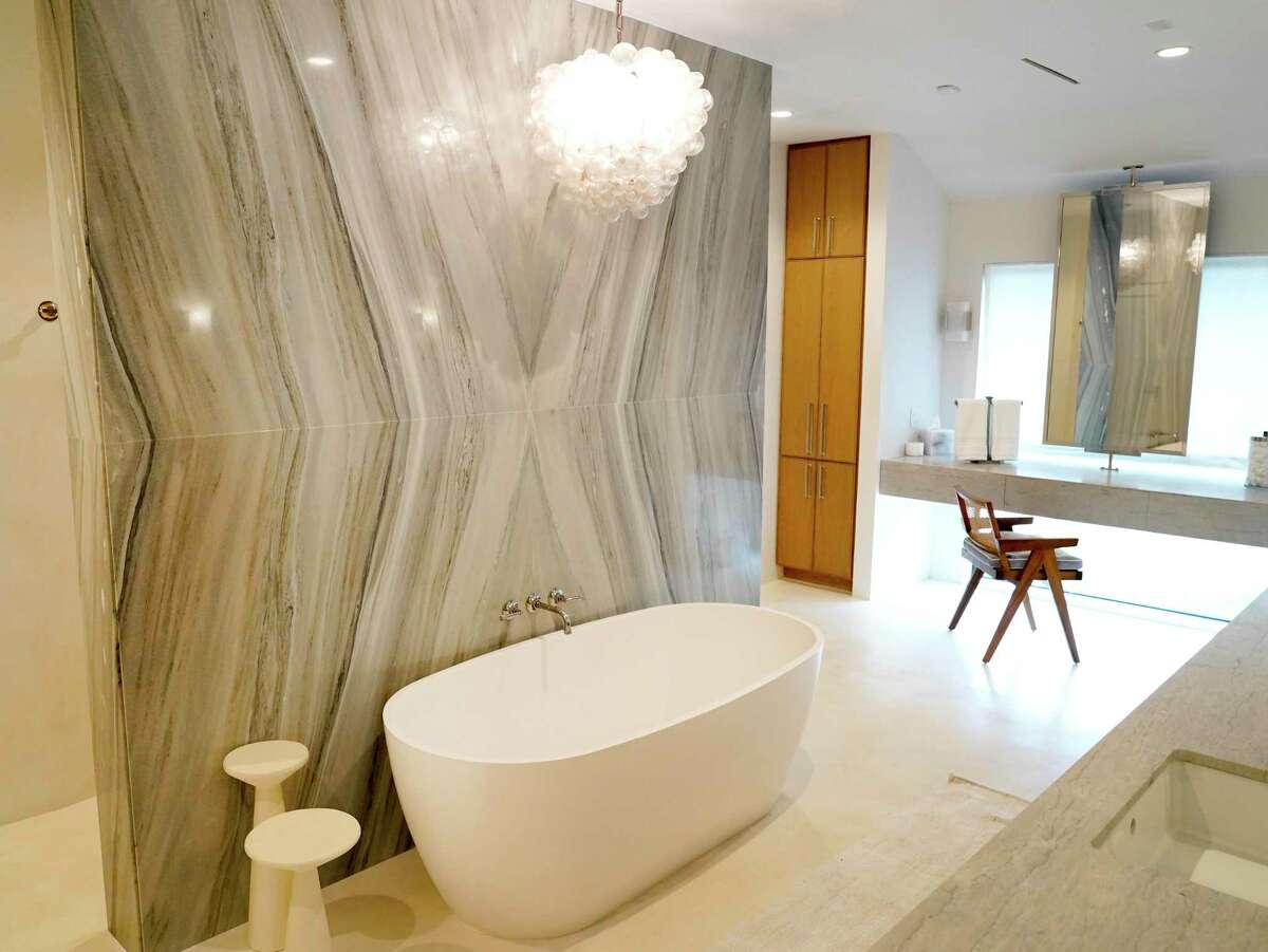 The home has been remodeled, and space in the bathroom was reimagined. Now, a freestanding tub sits in front of bookmatched slabs of marble, hiding a wide shower behind it.