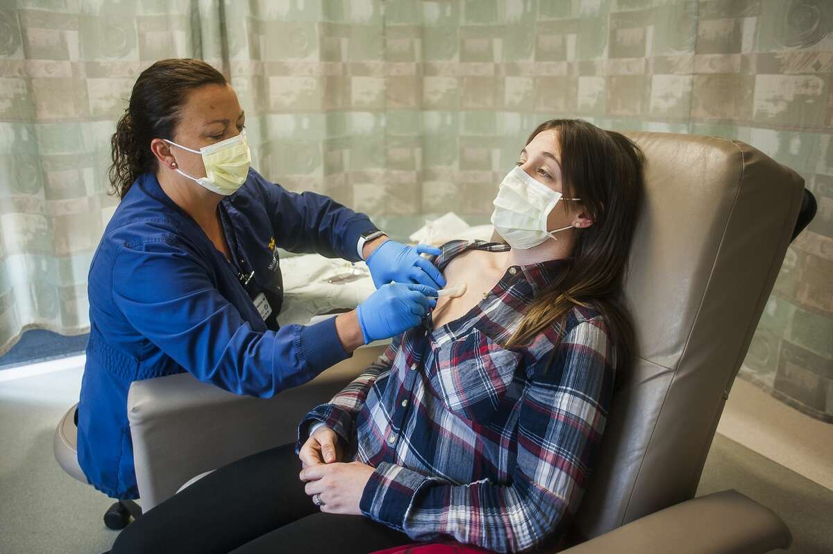 Tasha Earegood sits back as Christine Mooney, an RN with MidMichigan Medical Center-Midland, left, cleans a port on Earegood's chest, which is used for administering chemotherapy, during an appointment Tuesday, May 7, 2019 at the Cancer Center in Midland. (Katy Kildee/kkildee@mdn.net)