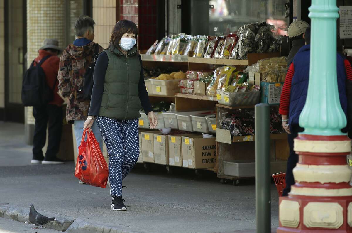 A masked shopper walks in the Chinatown district of San Francisco on Friday, Jan. 31, 2020. As China grapples with the growing coronavirus outbreak, Chinese people in California are encountering a cultural disconnect as they brace for a possible spread of the virus in their adopted homeland. (AP Photo/Ben Margot)