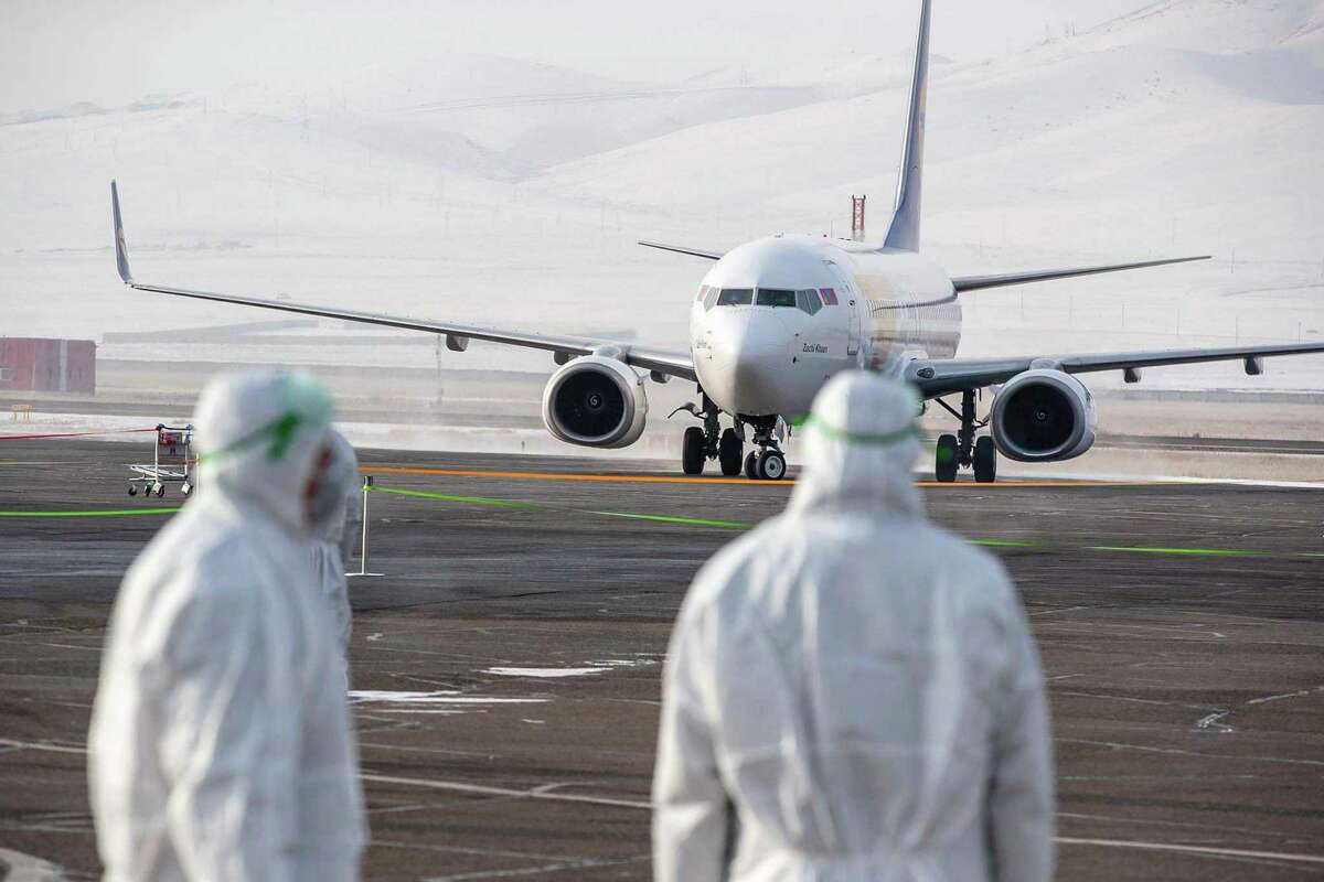 File photo: Staff members, wearing protective suits, watch as a plane carrying 32 Mongolian citizens for their evacuation from the Chinese city of Wuhan arrives in Ulaanbaatar, the capital of Mongolia on February 1, 2020.