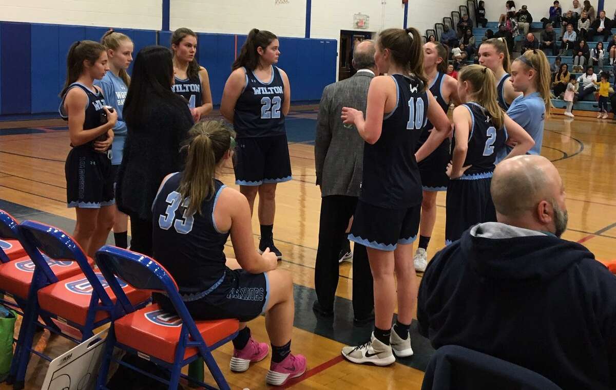 The Wilton girls basketball team gathers around coach Fred Francello during a timeout in Thursday's game at Danbury.