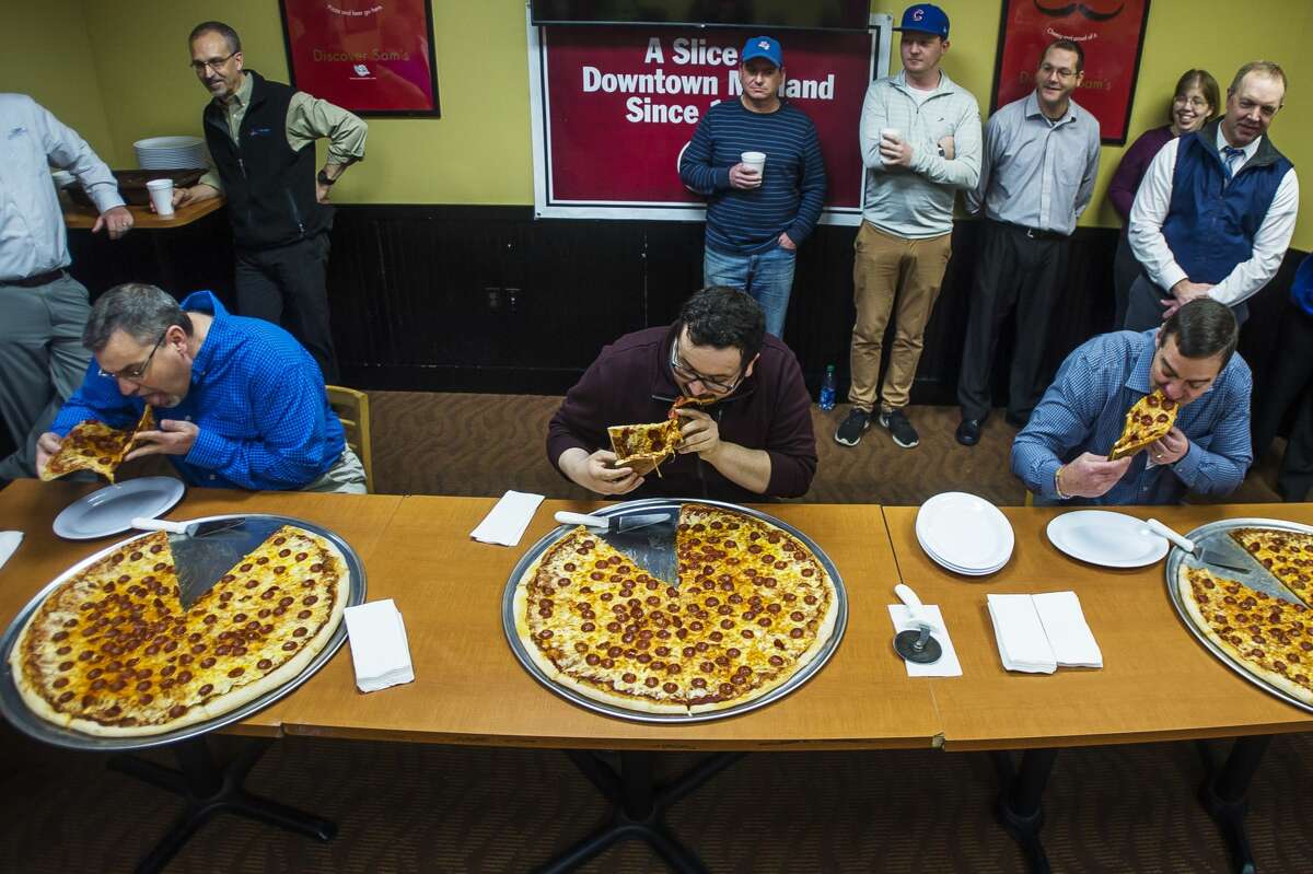 Competitors take their first bites during a pizza eating contest hosted by the Midland Daily News and Pizza Sam's Monday, Feb. 3, 2020 at the restaurant. (Katy Kildee/kkildee@mdn.net)