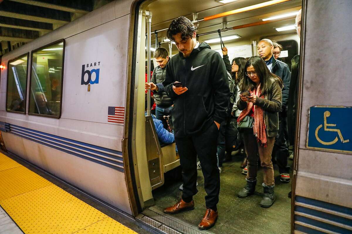 A man (declined name) and others look at their phones as they ride the BART train at the Balboa Park station on Wednesday, Sept. 25, 2019 in San Francisco, California.The Balboa Park station experiences the most cell phone and laptop thefts in the city.