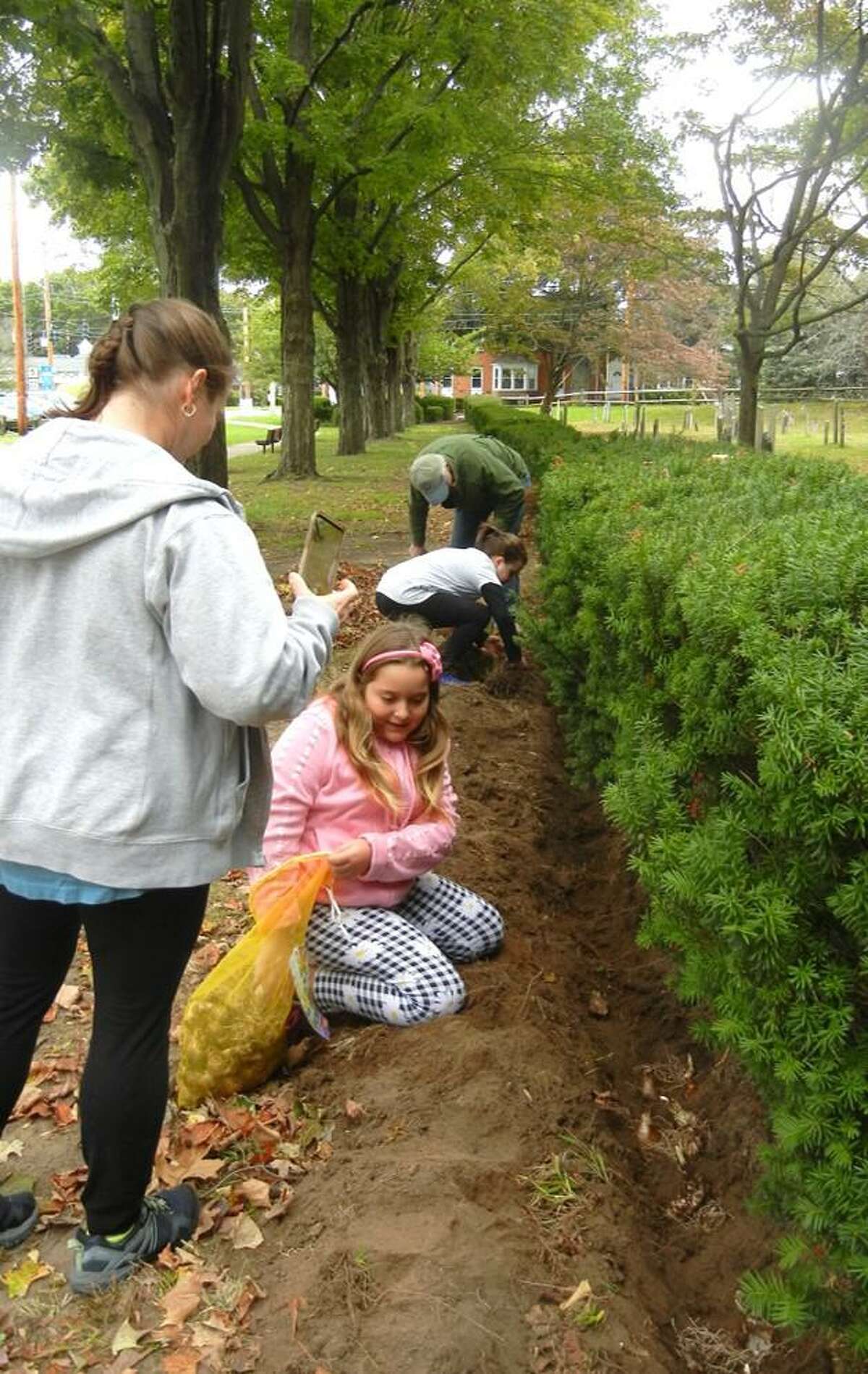 Ava and Abby plant bulbs with some assistance from members of the Daytime Gardeners.