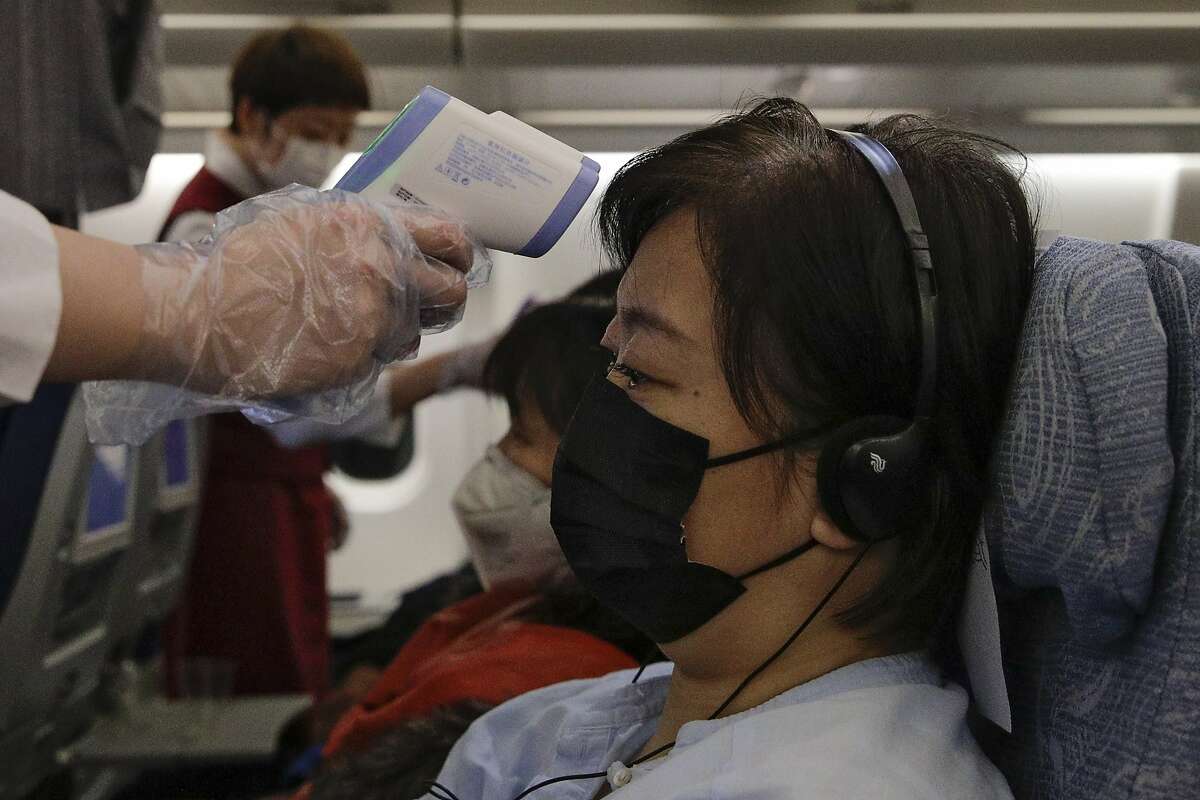 Stewardesses take temperatures of passengers as a preventive measure for the coronavirus on an Air China flight from Melbourne to Beijing before it land at Beijing Capital International Airport in China, Tuesday, Feb. 4, 2020.