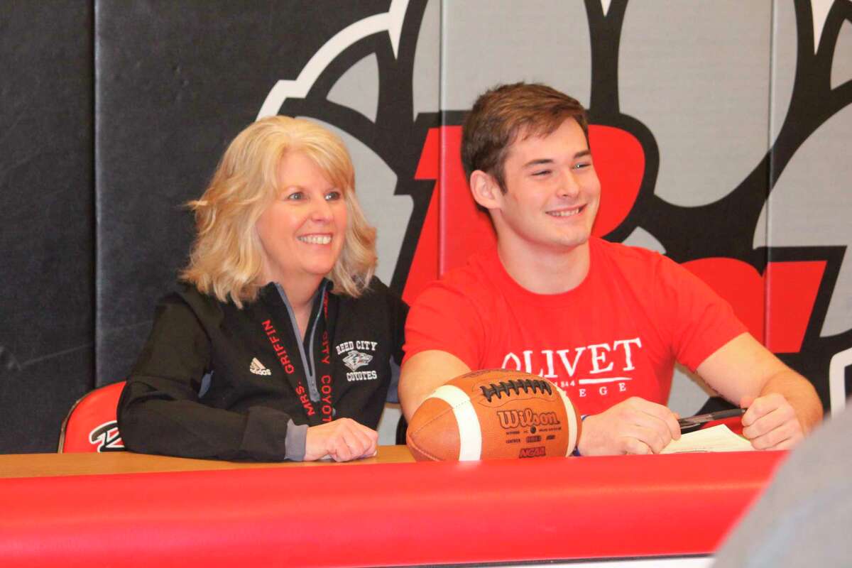 Reed City athletic director Kris Griffin (left) congratulates Coyote athlete Austin Fowler on his decision to play football and run track at Olivet College. (Pioneer photo/John Raffel)