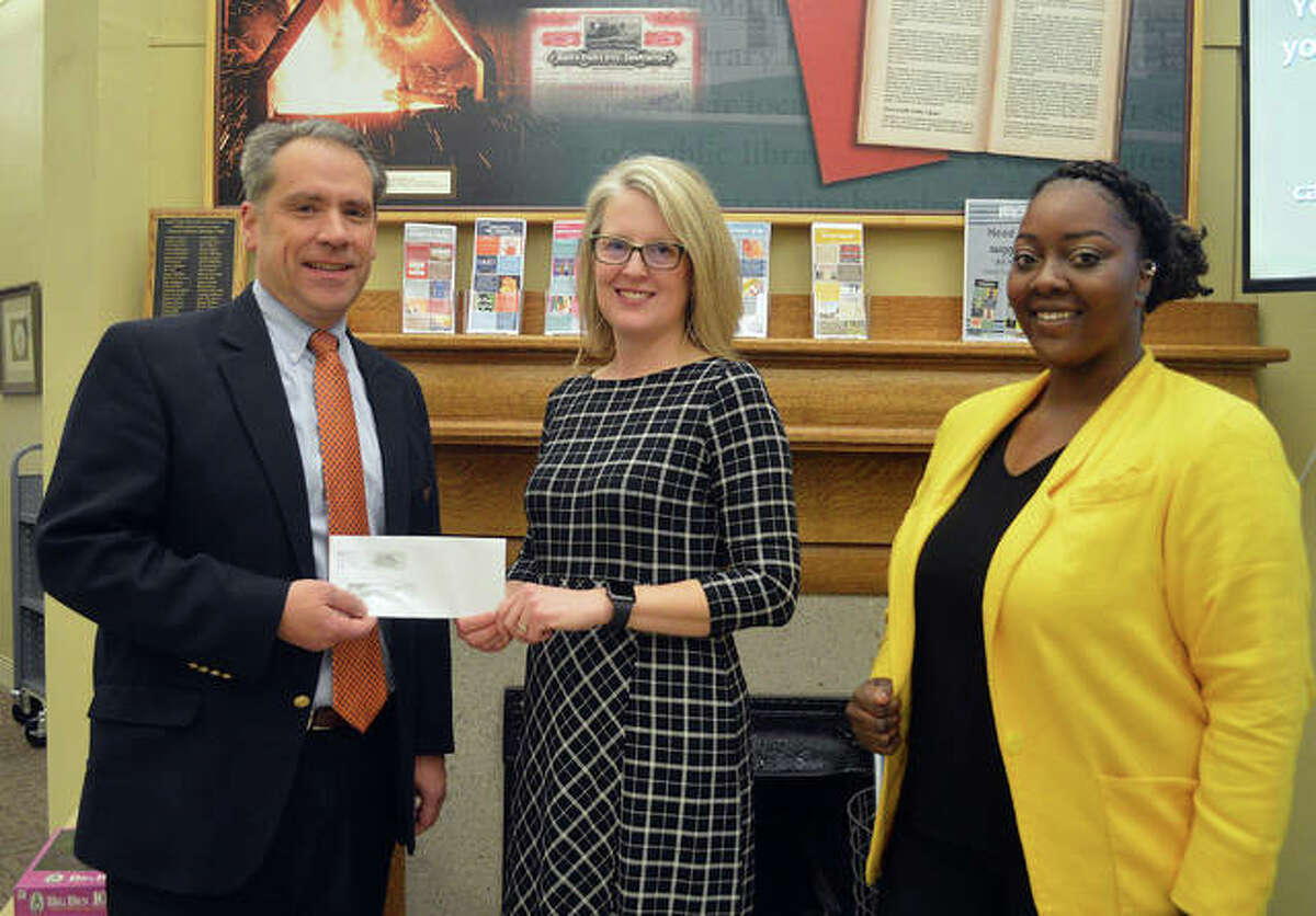 Dave Toby, left, senior vice president of FCB Banks in Edwardsville, hands a check for $2,500 to Edwardsville Public Library Director Schardt as Brejani Owens, the library’s new social work intern from SIUE, looks on. The money from FCB Banks will help pay for an MSW (a person with a master’s degree in social work) to supervise Owens’ practicum.