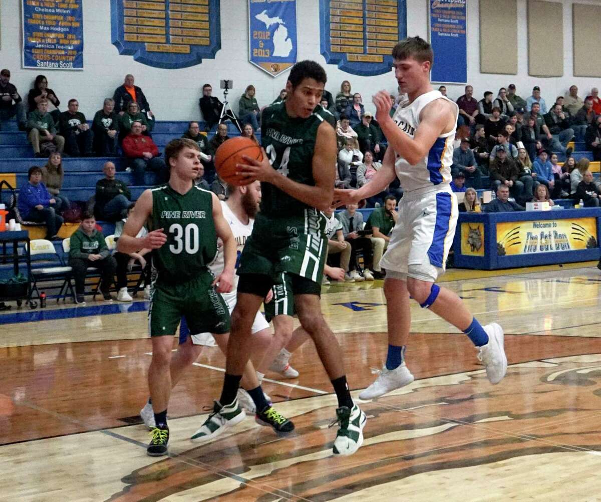 Marcus Jurik of Pine River comes down with a rebound on defense while Evart's Donavin Reagan also goes for the ball during Evart's victory on Wednesday night. (Pioneer photo/Joe Judd)