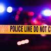 Accident or crime scene cordon tape, police line do not cross. It is nighttime, emergency lights of police cars flashing blue, red and white in the background