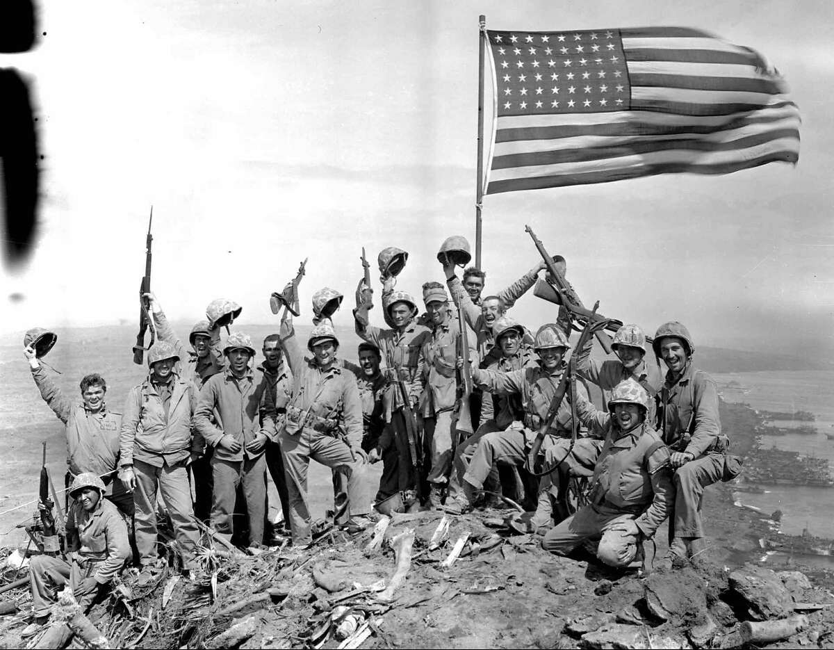 ADVANCE FOR SUNDAY, FEB. 12--FILE--Marines of the 28th Regiment, Fifth division, cheer after raising the American flag at the top of Mount Suribachi, Iwo Jima, on Feb. 23, 1945. AP photographer Joe Rosenthal posed the group shortly after he made his famous flag-raising picture. The dark marks at the upper left are from damage to the original negative.(AP Photo/Joe Rosenthal,File)
