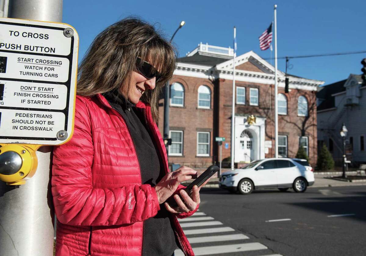 Leslie Costa of Ridgefield checks her cell while walking Main Street, Ridgefield, on Monday, Feb. 3, 2020. The town is considering providing free Wi-Fi in the village area.