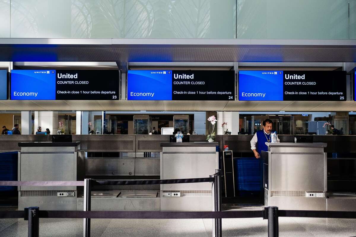 A lone baggage handler stands at empty United Airlines kiosks at the International departures area at San Francisco International Airport in San Francisco, Calif. on Tuesday, February 4, 2020.