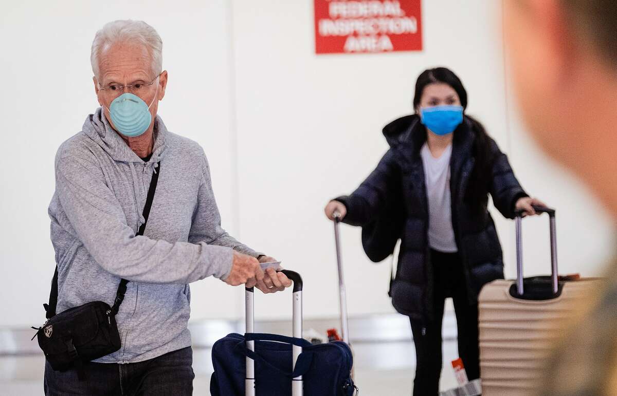 Passengers are seen wearing masks at the International arrivals area at San Francisco International Airport in San Francisco, Calif. on Tuesday, February 4, 2020.