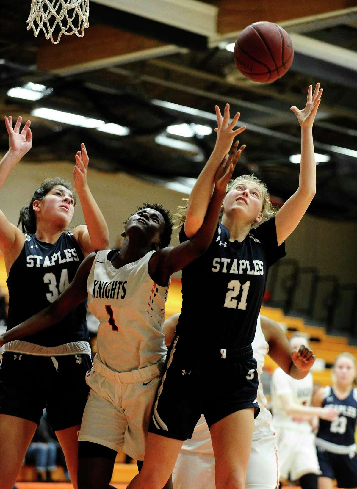 Stamford’s Breanna Jacobs fights for a rebound with Staples’ Ariana Gerig (34) and Marisa Shurrock (21) in the first half of Thursday’s game at Kuzco Gymnasium in Stamford.