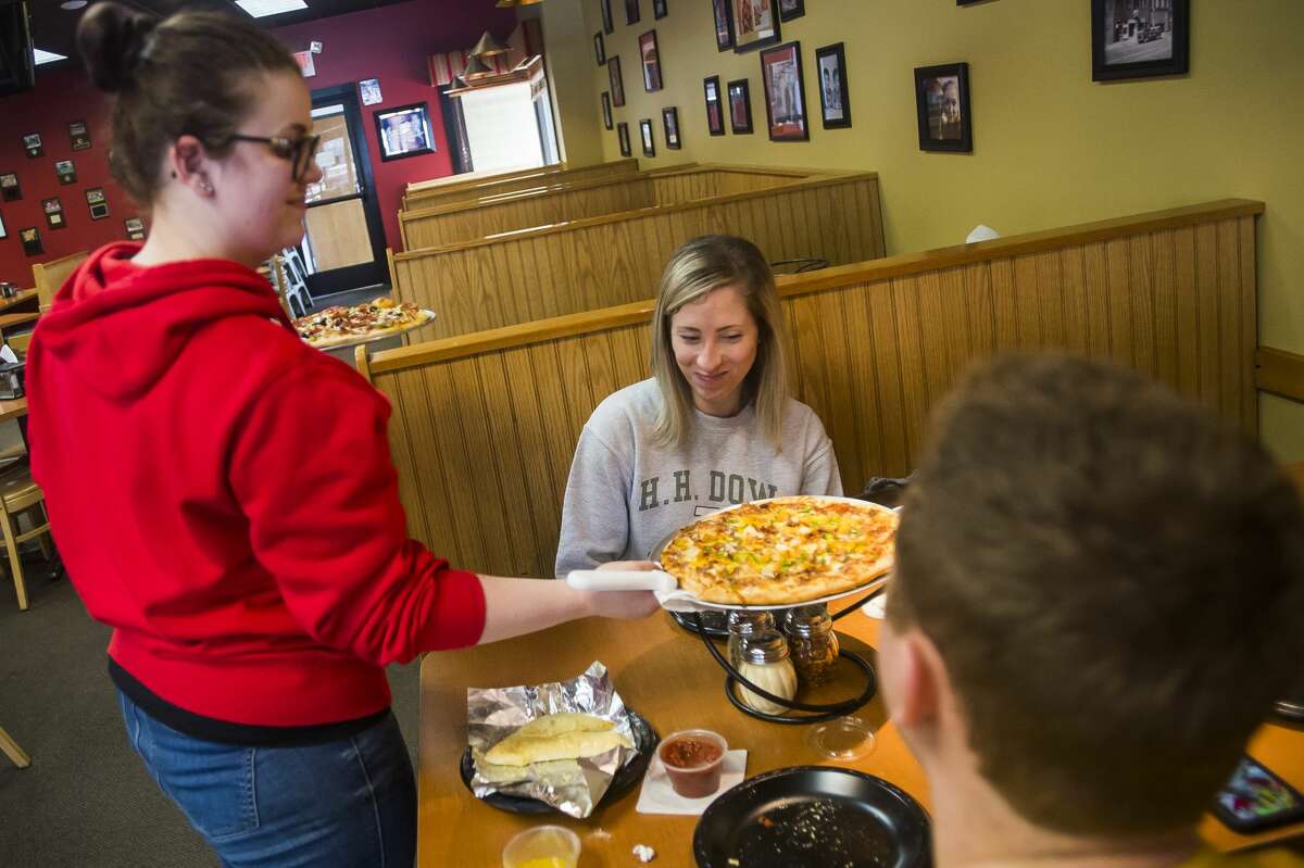 Grace Lewis serves a pizza to customers Friday, Feb. 7, 2020 at Pizza Sam's. (Katy Kildee/kkildee@mdn.net)