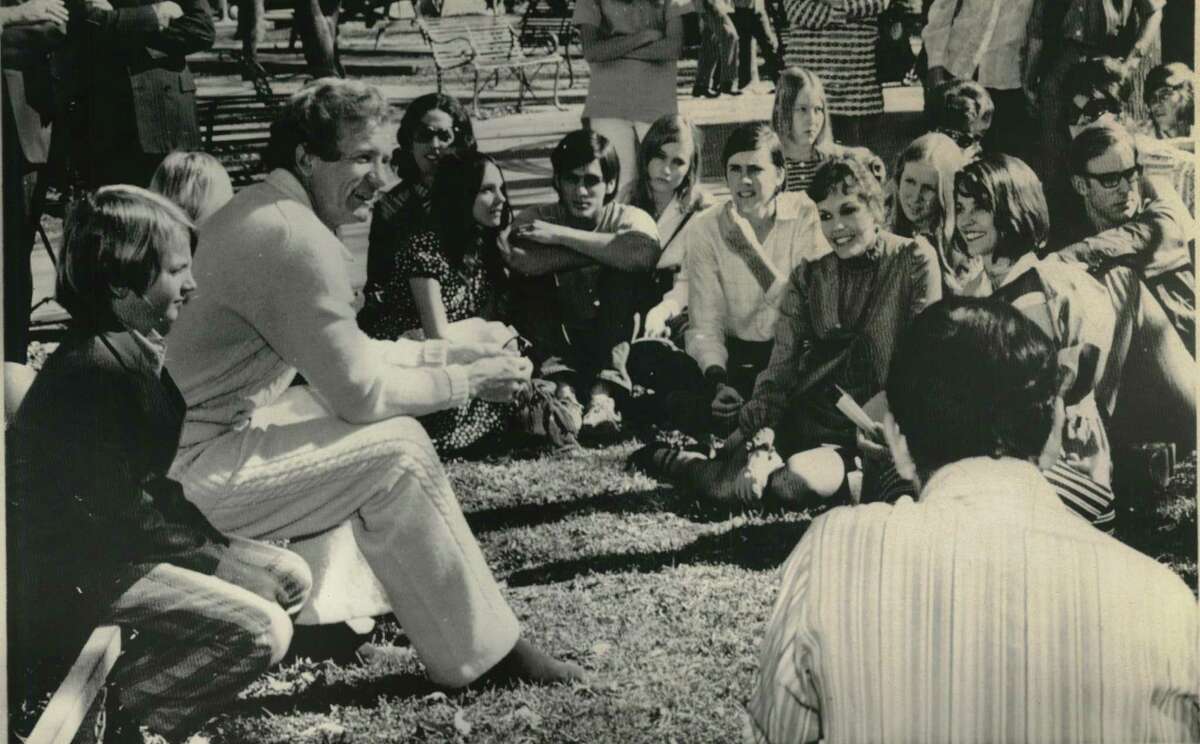The Reverend Wil Schaefer, ousted pastor of First United Methodist Church, talks to church members last Sunday after his dismissal was announced. Sitting next to Schaefer is his son, Stuart, 10. Seated on the grass at right are Mrs. Judy Nash of San Antonio (short hair), with whom Schaefer has admitted having a romantic relationship; and Mrs. Rita Schaefer, his wife.