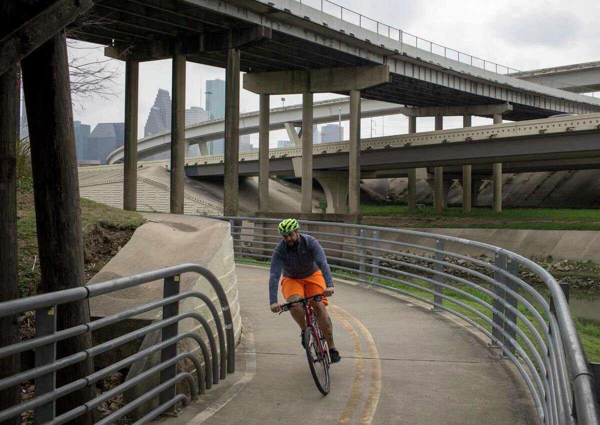 A cyclist rides along the White Oak Bayou Greenway Trail on Tuesday, Feb. 4, 2020, at in Houston. In the background, Hogan Street crosses over IH-45, north of Downtown Houston.