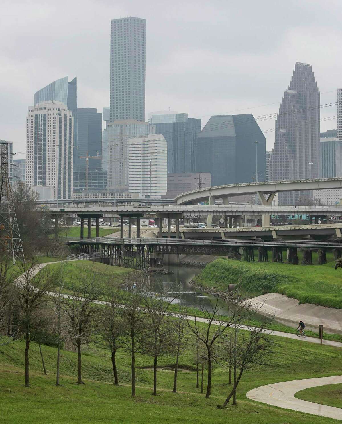 A cyclist rides along the White Oak Bayou Greenway Trail on Feb. 4, 2020, in Houston. In the background, Hogan Street crosses over Interstate 45, north of downtown Houston.