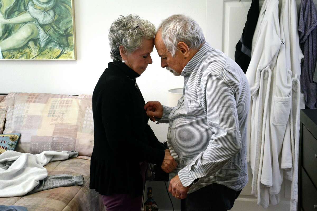 Vicki Axe, 71, dresses her husband Harold Axe, 77, in their Fishkill home.