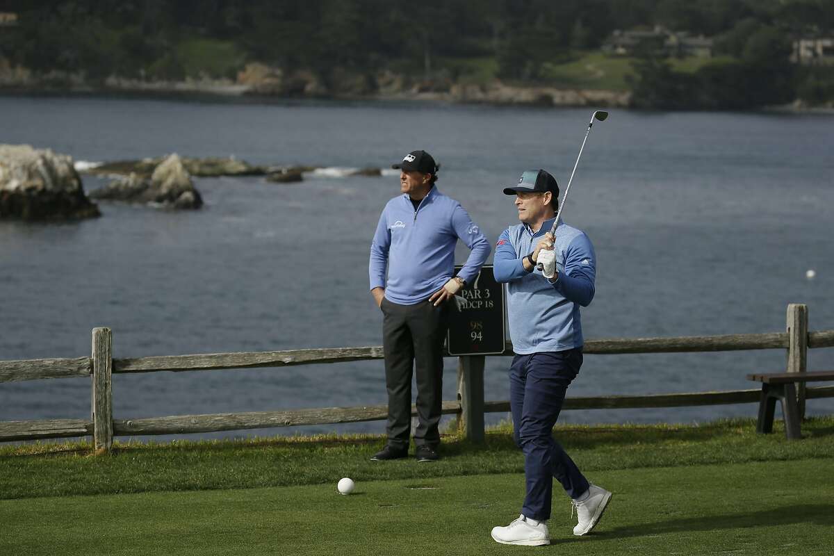 Steve Young follows his shot from the seventh tee of the Pebble Beach Golf Links as Phil Mickelson looks on during the third round of the AT&T Pebble Beach National Pro-Am golf tournament Saturday, Feb. 8, 2020, in Pebble Beach, Calif. (AP Photo/Eric Risberg)