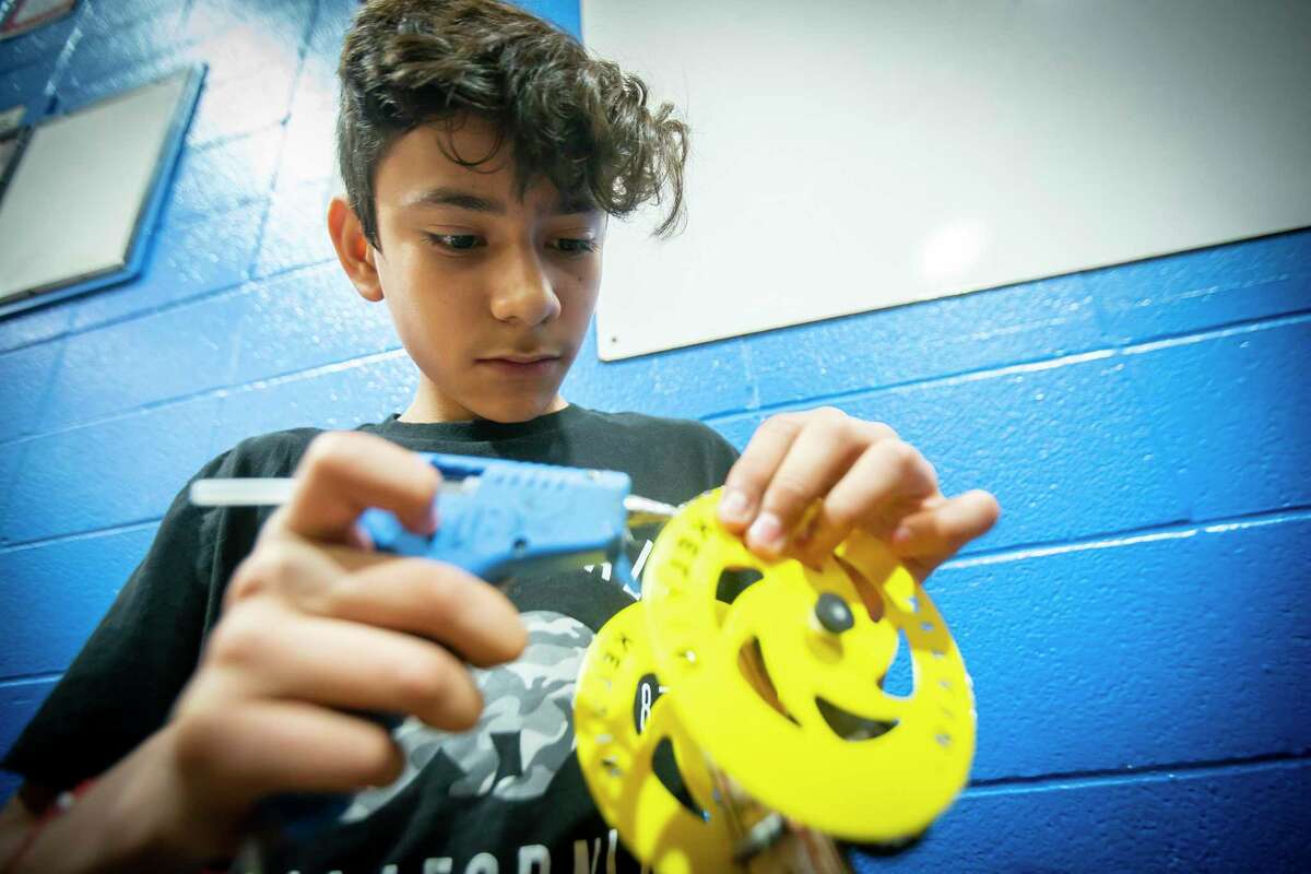 Holland Middle School seventh-grader Emilio Muñoz puts glue on the wheels of his mouse trap-powered car hoping to add traction during a competition hosted by ExxonMobile and SECME, an organization committed to bring more underrepresented students into the engineering field, Saturday, Feb. 8, 2020, at Holland Middle School in Houston.