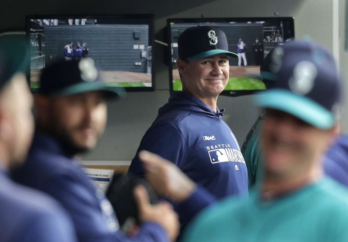 FILE - In this April 12, 2019 file photo, Seattle Mariners manager Scott Servais, center, smiles in the dugout before a baseball game against the Houston Astros in Seattle. Spring training for the Mariners ahead of the 2020 season will feature young players and prospects that could be at the heart of whether the Mariners' rebuild plans ultimately work. (AP Photo/Ted S. Warren, File)