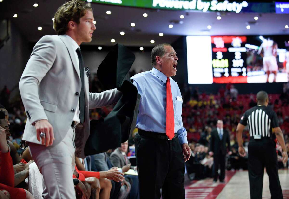 Houston head coach Kelvin Sampson, right, hands his jacket to graduate assistant Landon Goesling during the first half of an NCAA college basketball game against Wichita State, Sunday, Feb. 9, 2020, in Houston.