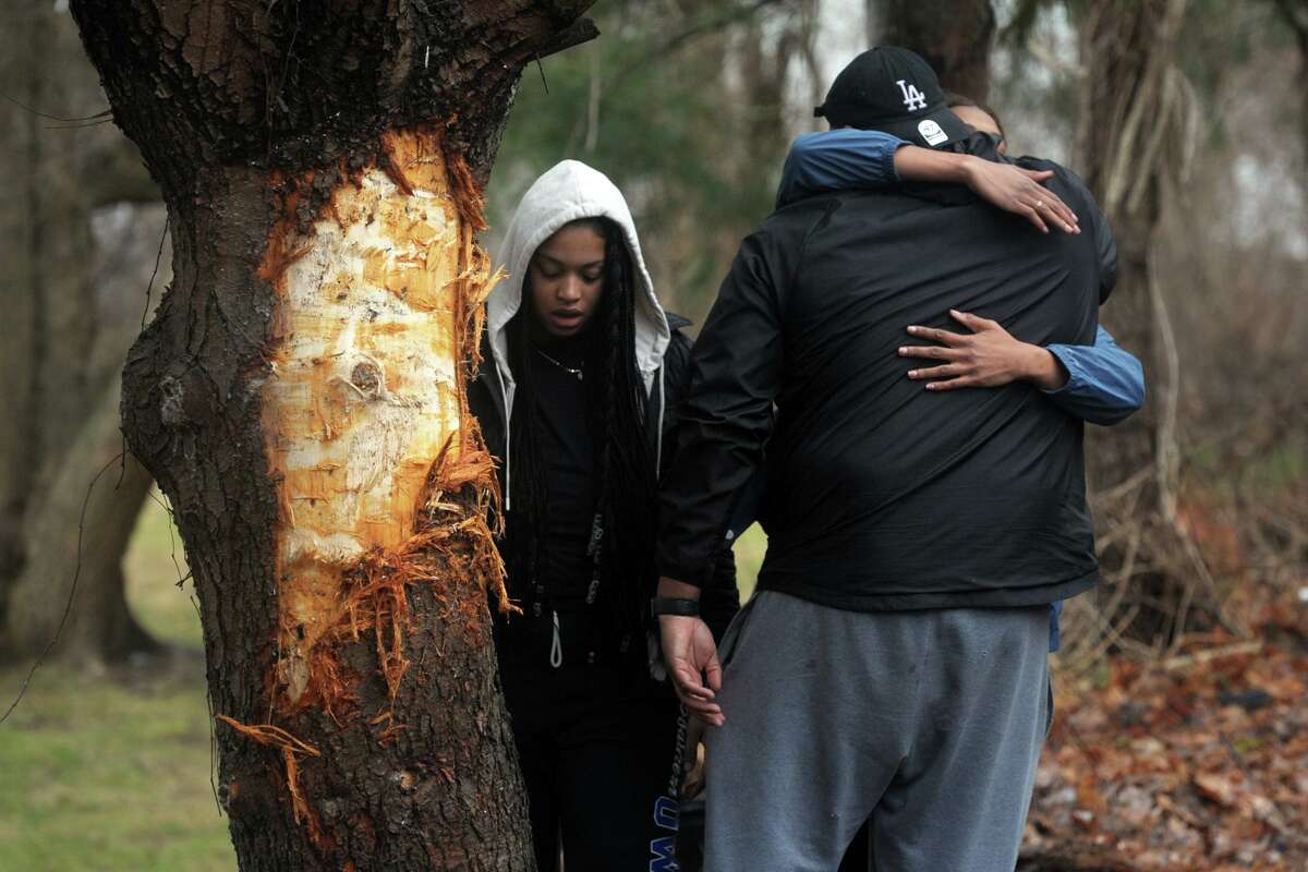 Three people gather next to a tree that was impacted by one of the two vehicles involved in a fatal accident that occurred on River Rd. in Shelton, Conn. shortly before midnight Sunday, seen here on Feb. 10, 2020. Police confirmed Monday morning that two people were killed in the accident.