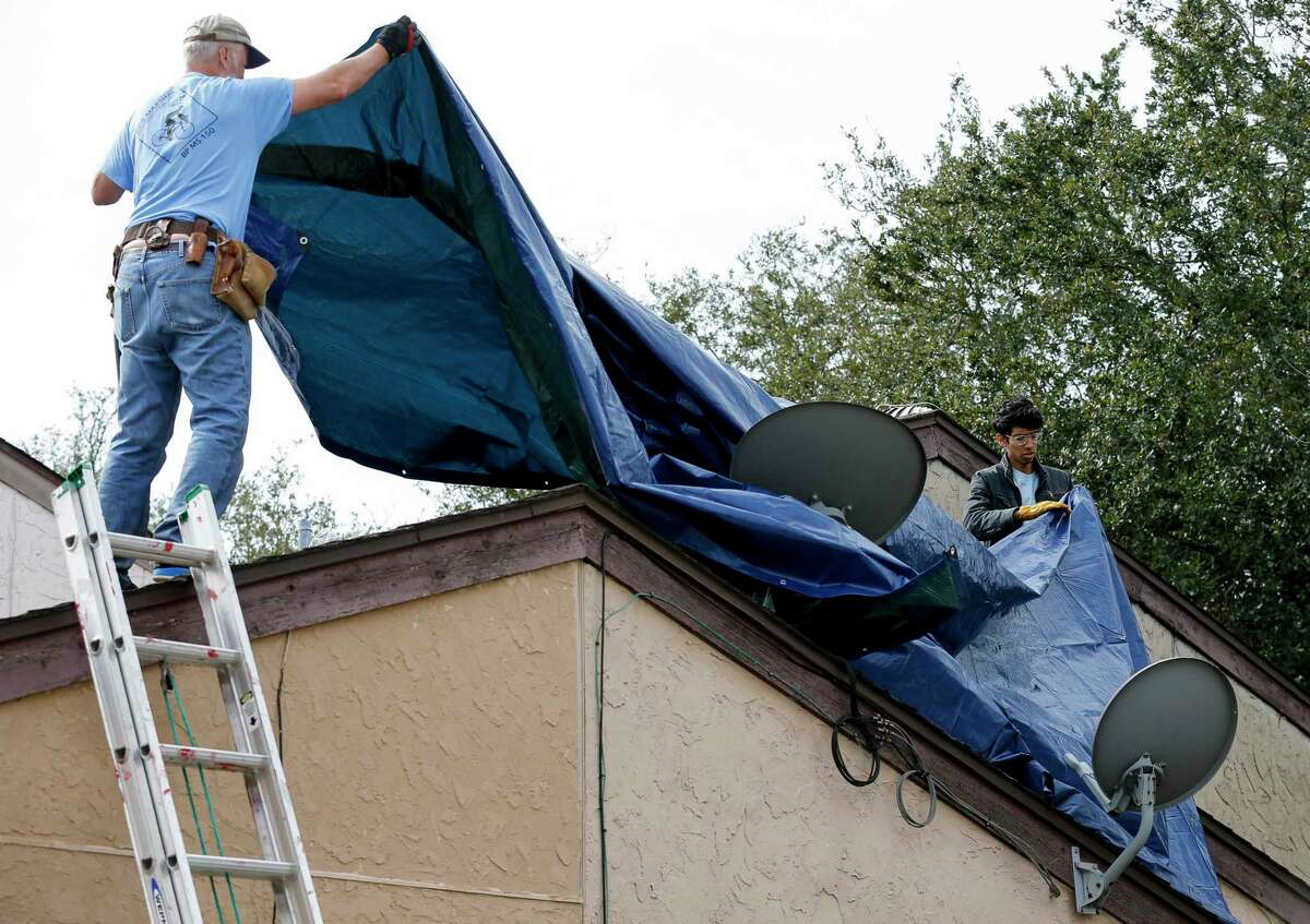 Volunteers work to cover the roof of a home in the Westbranch neighborhood to prevent further damage by the projected rain Saturday, Jan. 25, 2020, in Houston. Many homes in the neighborhood were severely damaged by the explosion at Watson Grinding and Manufacturing.