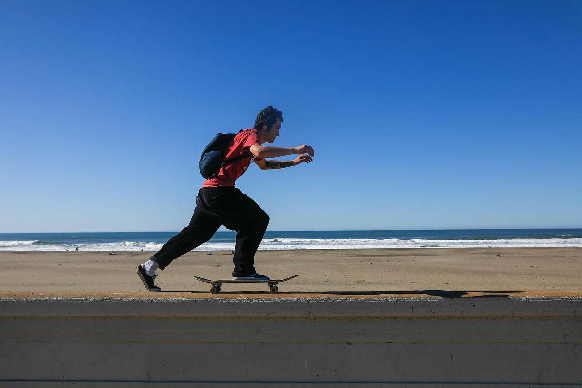 Adam Castro skates along the wall Ocean Beach on a sunny day on Monday, Feb. 10, 2020 in San Francisco, California. He was making his way to work.