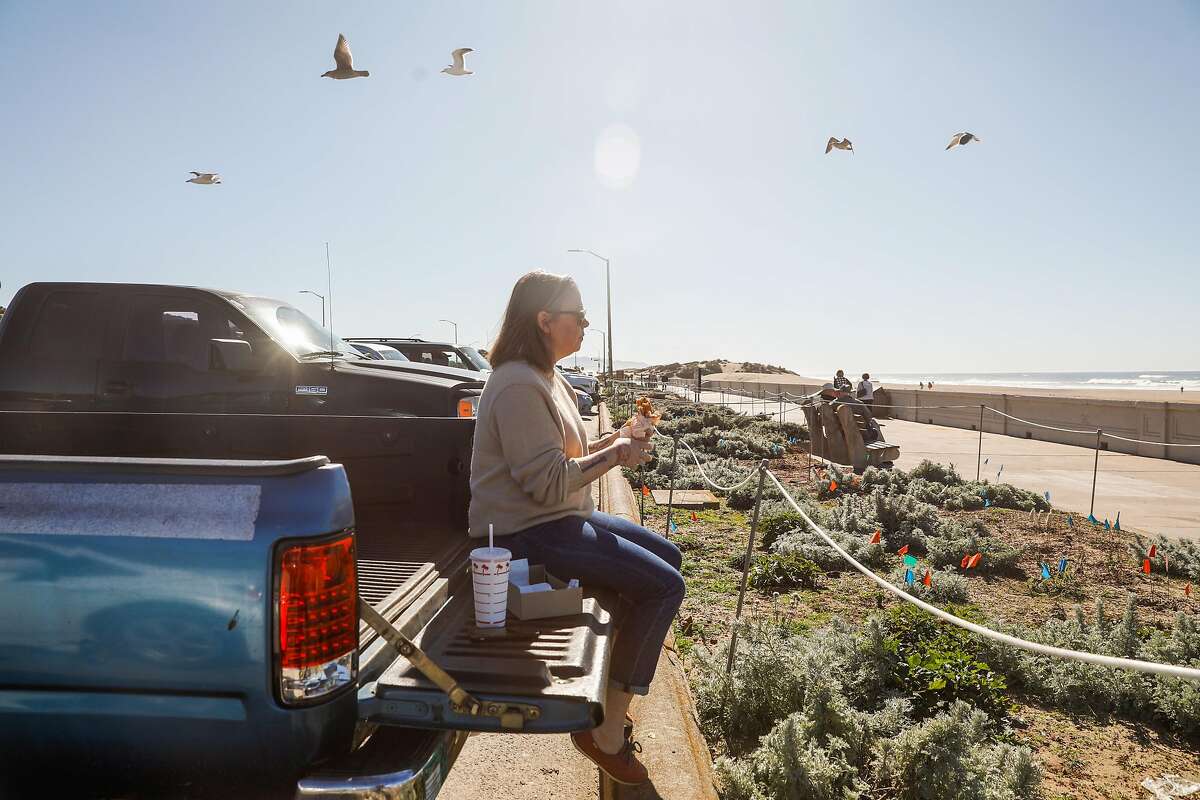 Jessica Furui eats a hamburger in the back of her truck at Ocean Beach on a sunny day on Monday, Feb. 10, 2020 in San Francisco, California. She drove from Daly City to have her lunch at the beach.