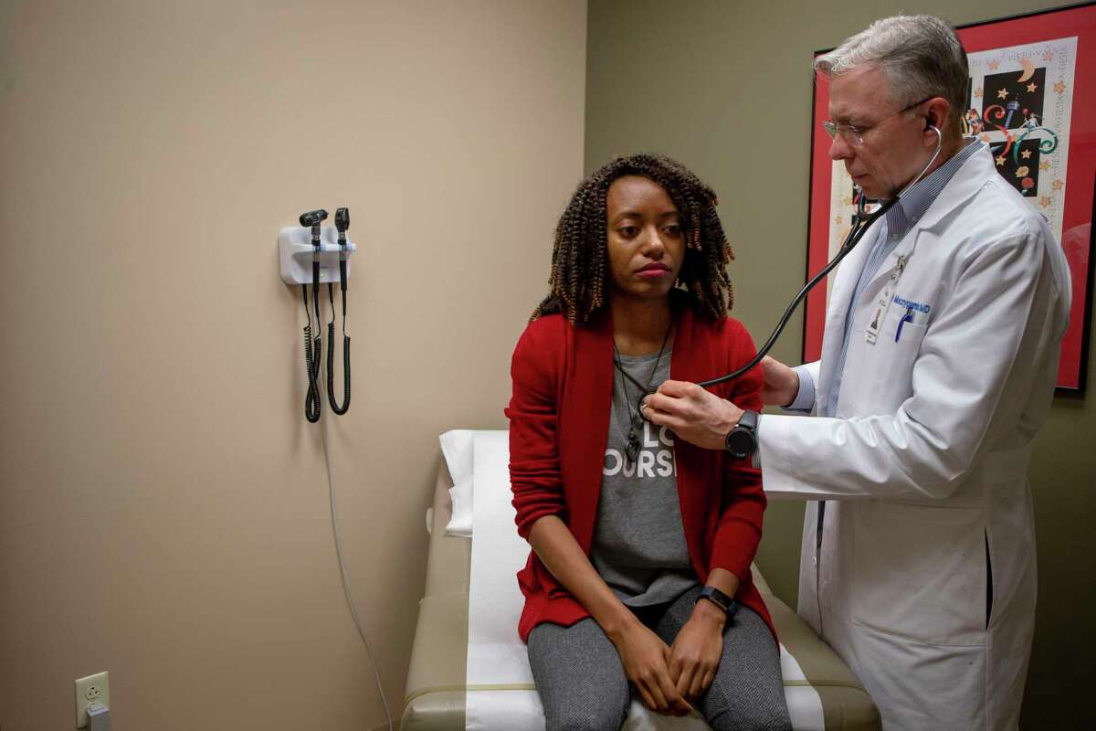 Dr. Roger Moczygemba checks the heartbeat of patient Antrea Ferguson at his direct-care practice Direct Med Clinic in San Antonio. Ferguson says her employer Shankx Web Dev covers her monthly membership and she pays $10 for visits when needed.