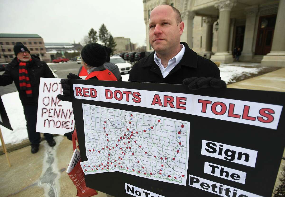 Patrick Sasser, of Stamford, and protestors from the group No Tolls CT, hold signs outside the Capitol in Hartford, Conn. on Wednesday, February 20, 2019.