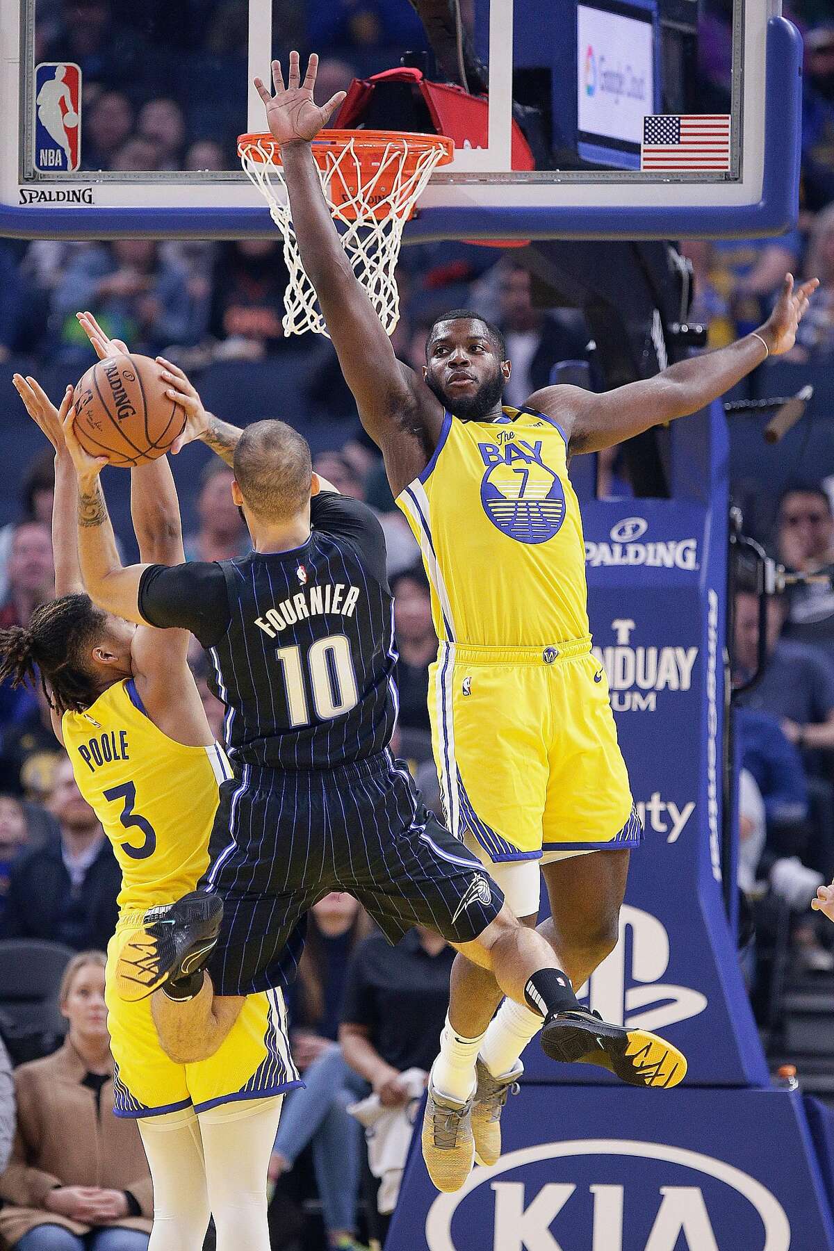 Golden State Warriors forward Eric Paschall (7) and Warriors guard Jordan Poole (3) defend Orlando Magic guard Evan Fournier (10) in the first half of an NBA game at Chase Center, Saturday, Jan. 18, 2020, in San Francisco, Calif.