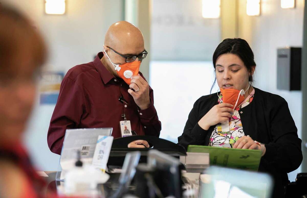 Wearing N95 face masks, from left to right, Clinic Manager Frank Perez and Back Medical Assistant Ericka Salcido confer at the front desk of the Foothill Community Health Center on Monday, February 10, 2020 in San Jose, California.