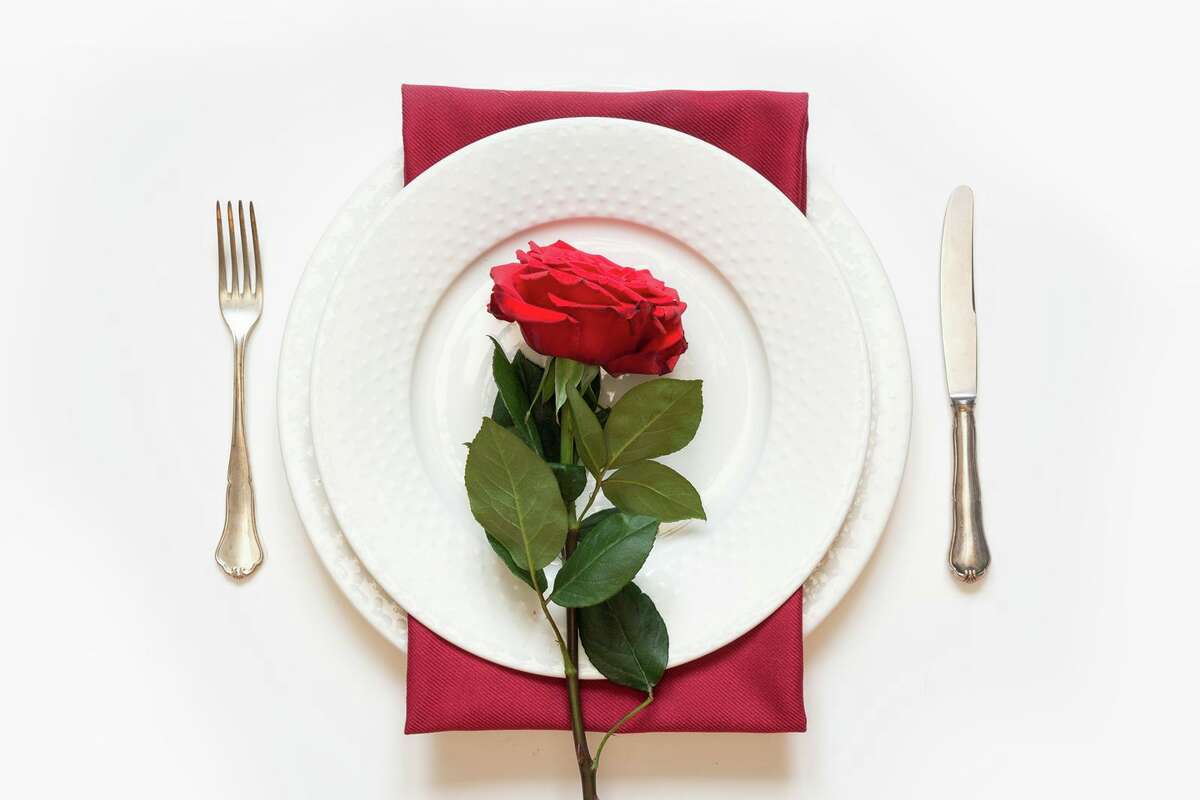 Valentine's day dinner with a romantic table setting with red rose.