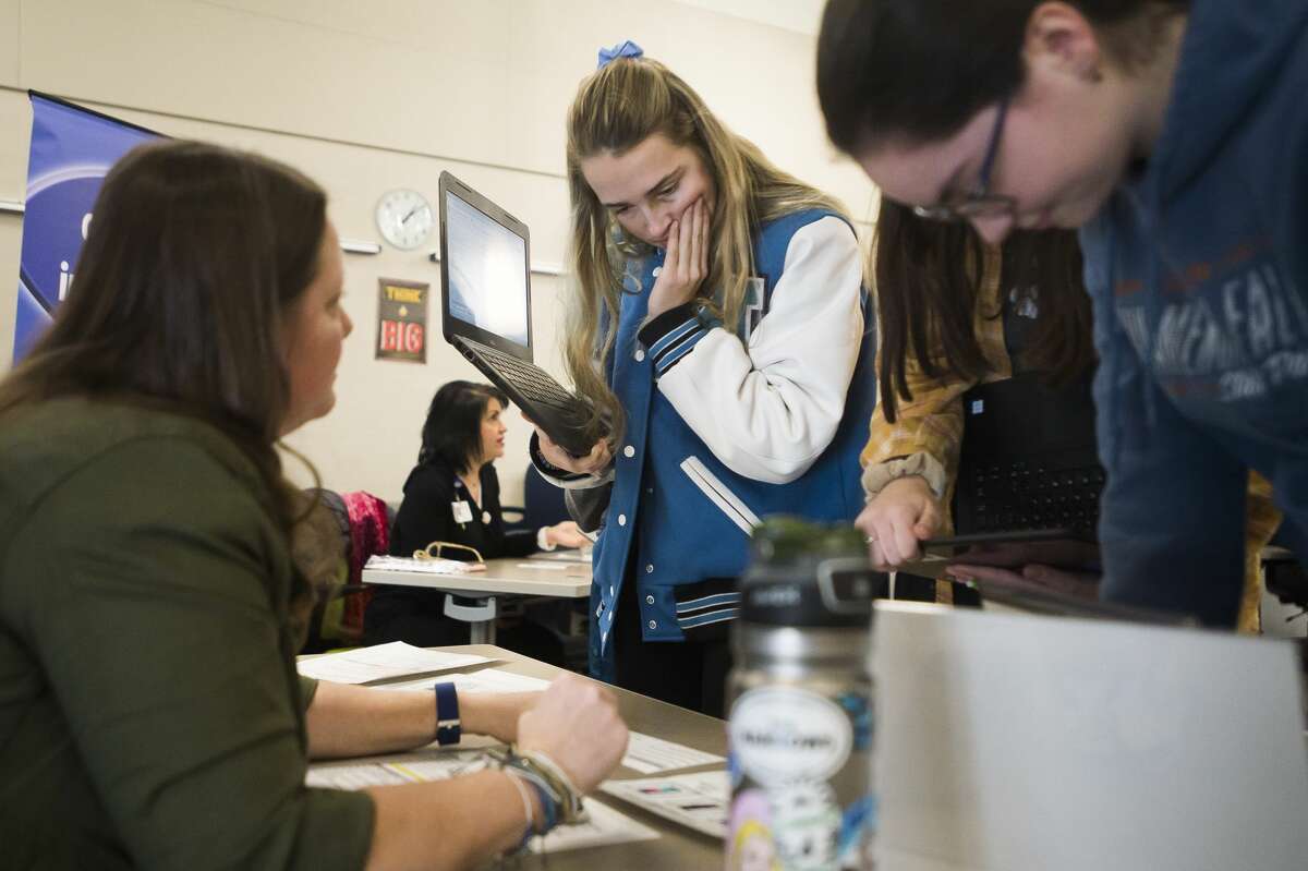 Hailey Sadler, center, contemplates which cell phone plan she will choose as she takes part in the "Reality Store," hosted by the Midland County Educational Service Agency, Tuesday, Feb. 11, 2020 at Meridian Early College High School. During the exercise, students select a career path, make financial decisions, and fill out a budget to simulate how those decisions will pan out. (Katy Kildee/kkildee@mdn.net)