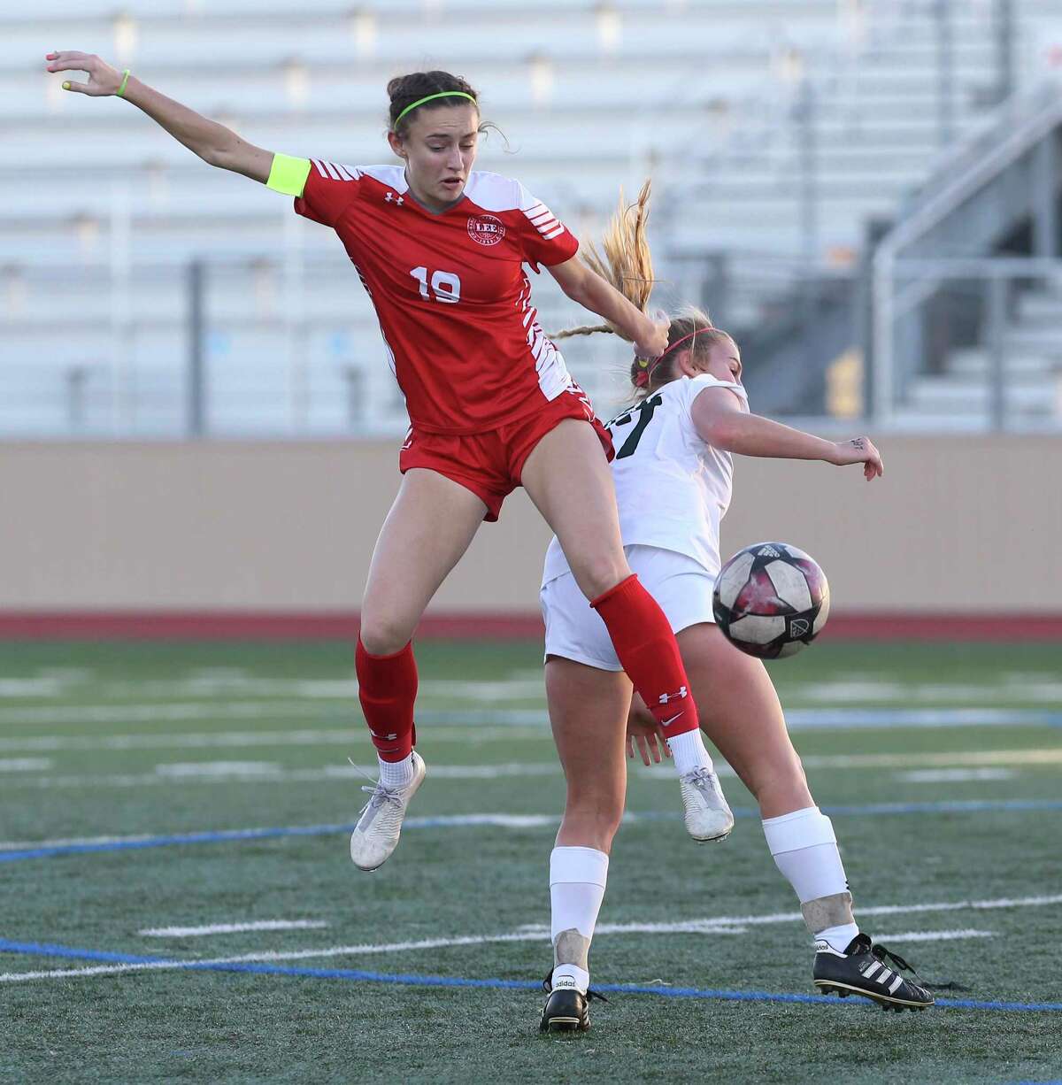 LEE's Jenevieve Jackson (19) and Reagan's Emma O'Brien (17) compete for the ball during their girls soccer game at Commander Stadium on Wednesday, Feb. 12, 2020. LEE defeated Reagan, 1-0.