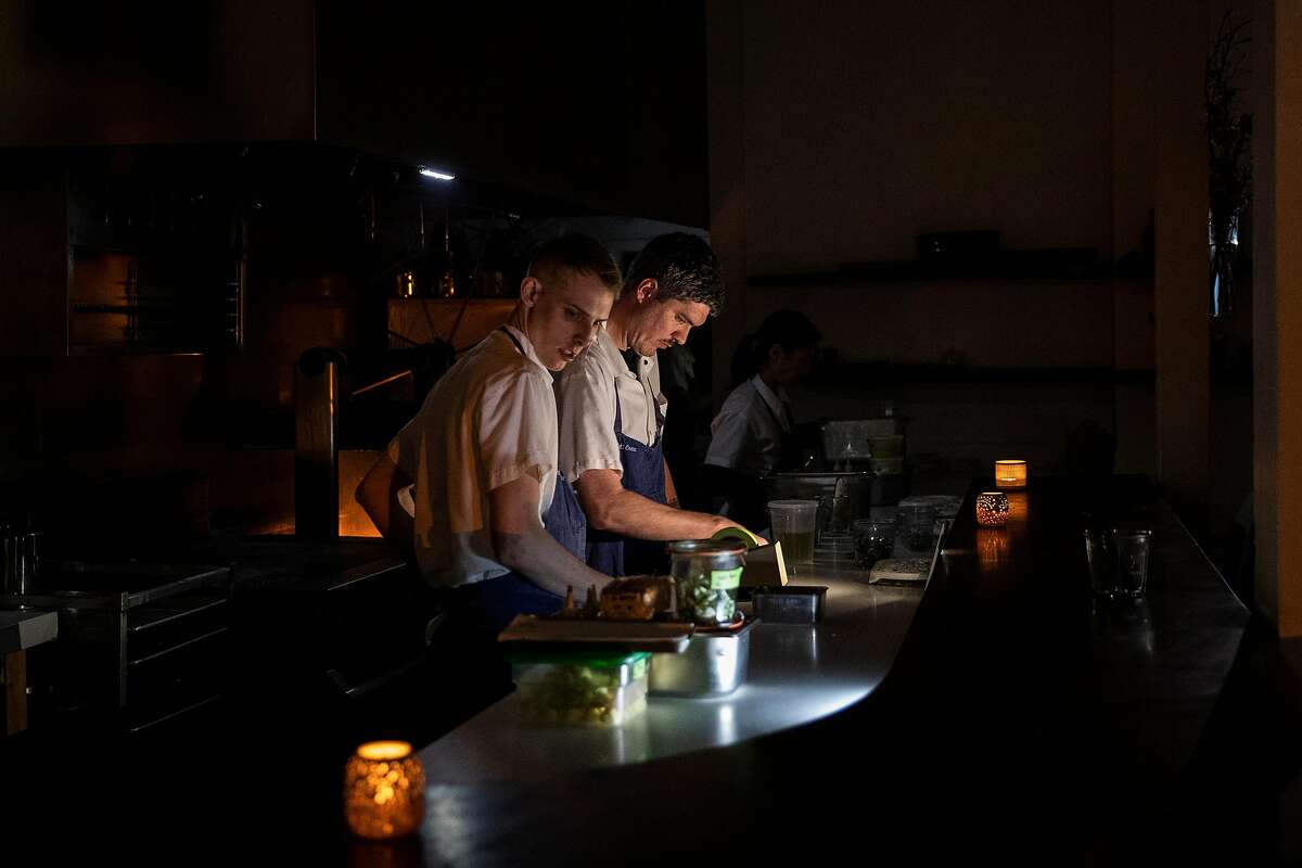 Staff members at Petit Crenn work under candlelight after an underground electrical transformer reportedly exploded, forcing the restaurant to close early in San Francisco, Calif. on Wednesday, Feb. 12, 2020.