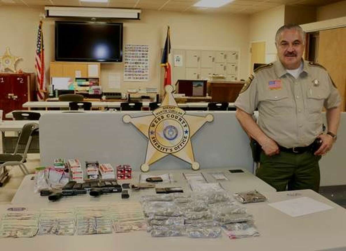 Webb County Sheriff Martin Cuellar stands next to the drugs, weapons and cash confiscated within the last several days.