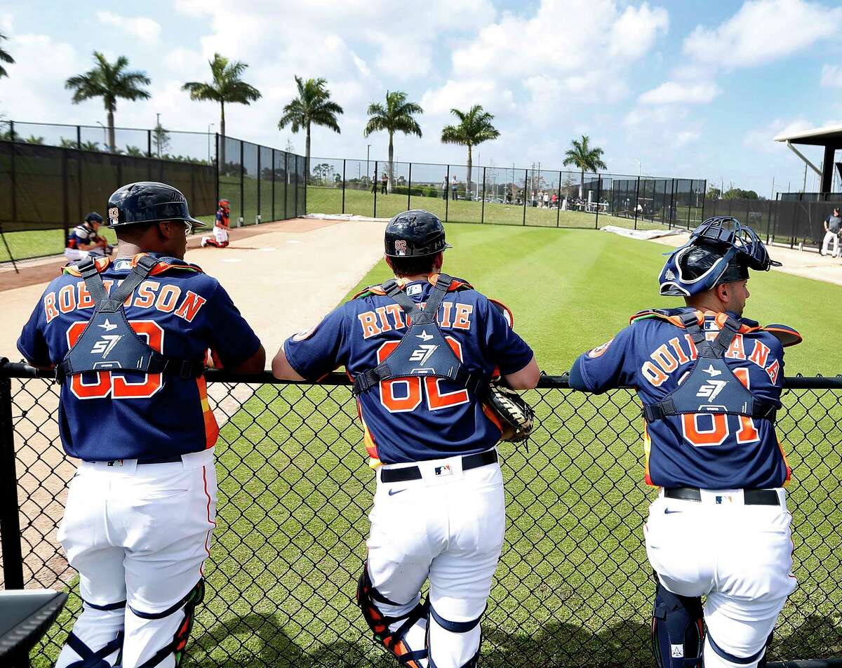 Houston Astros catchers Chuckie Robinson (83), Jamie Ritchie (82), and Lorenzo Quintana (81) wait their turns to catch pitchers during the first day of the Houston Astros pitchers and catchers spring training workout at the Fitteam Ballpark of The Palm Beaches, in West Palm Beach , Thursday, Feb. 13, 2020.