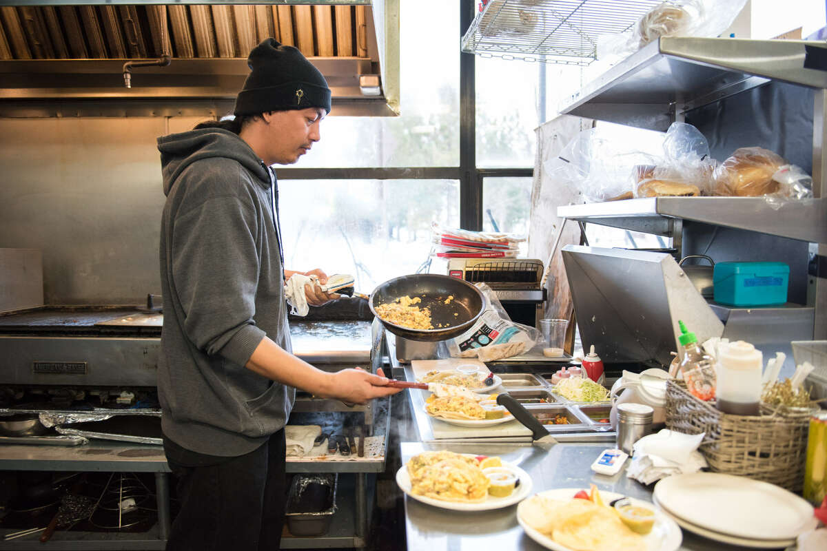 Billyjoe Aquino, a manager at Kings Cafe, works steadily in the kitchen preparing breakfast for a few regulars.