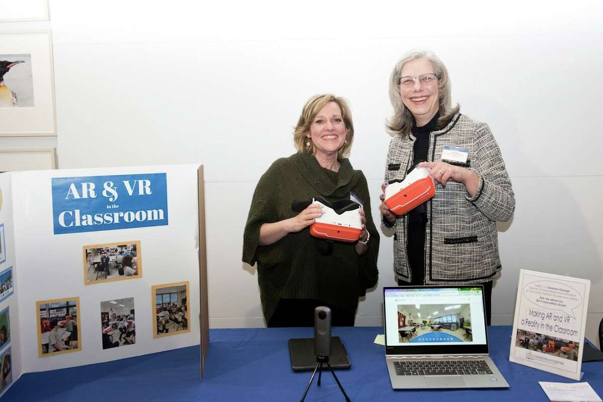 Deanna George, left, technology coordinator at Holy Trinity Catholic Academy and 2019 grant recipient, demonstrates Virtual Reality in the Classroom at the evening’s festivities. George is with HTCA Head of School Lisa Lanni.
