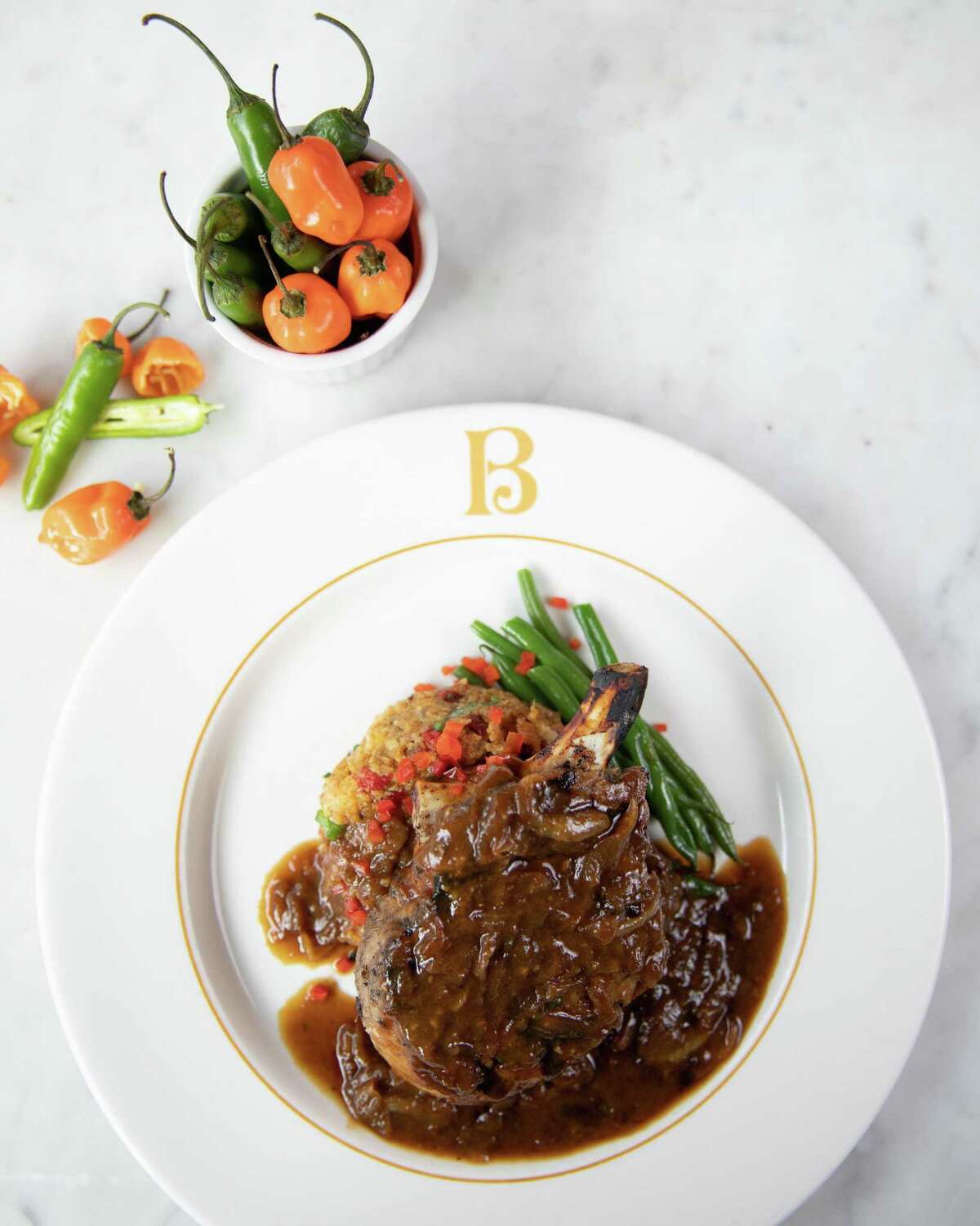 Creole-spiced smothered pork chops from a heritage menu to mark the 100-year anniversary of Broussard's Restaurant.