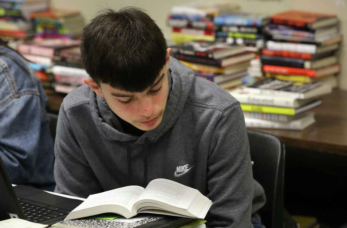 Cesar De La Garza reads a book from Michael Guevara’s classroom library at Southwest High School. At some schools, in-class libraries are the only option for student readers.