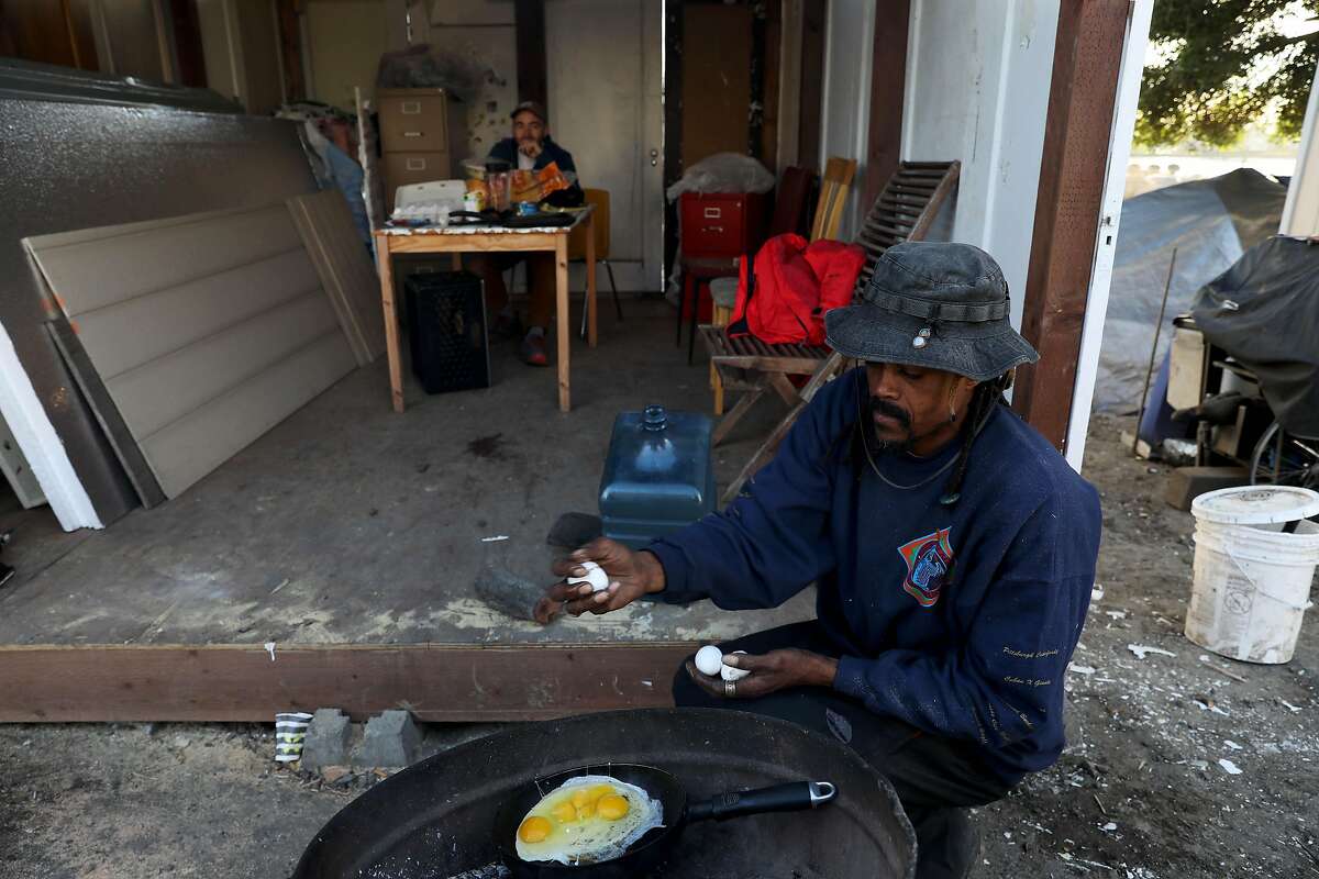 Ayat Jalal, 46, co-founder of First They Came For the Homeless, fries eggs as he makes dinner at a tiny home community called the Right to Exist Curbside Community, located off of E. 12th St. in Oakland, Calif., on Tuesday, February 4, 2020. Jalal has lived at the site since MLK Day. Currently there are eight tiny homes and one cob house at the location. Oakland and Berkeley city councils have committed to building self governing encampments to address the homeless crisis in their cities. But neither city really has put any full proof plan forward as to what a self governing is and how it should function. Berkeley is one step closer by directing staff to identify locations. Oakland however, is not. Instead, advocates in Oakland have resorted to building tiny home villages throughout the city -- unsanctioned -- as an example of what a self-governing encampment should look like.
