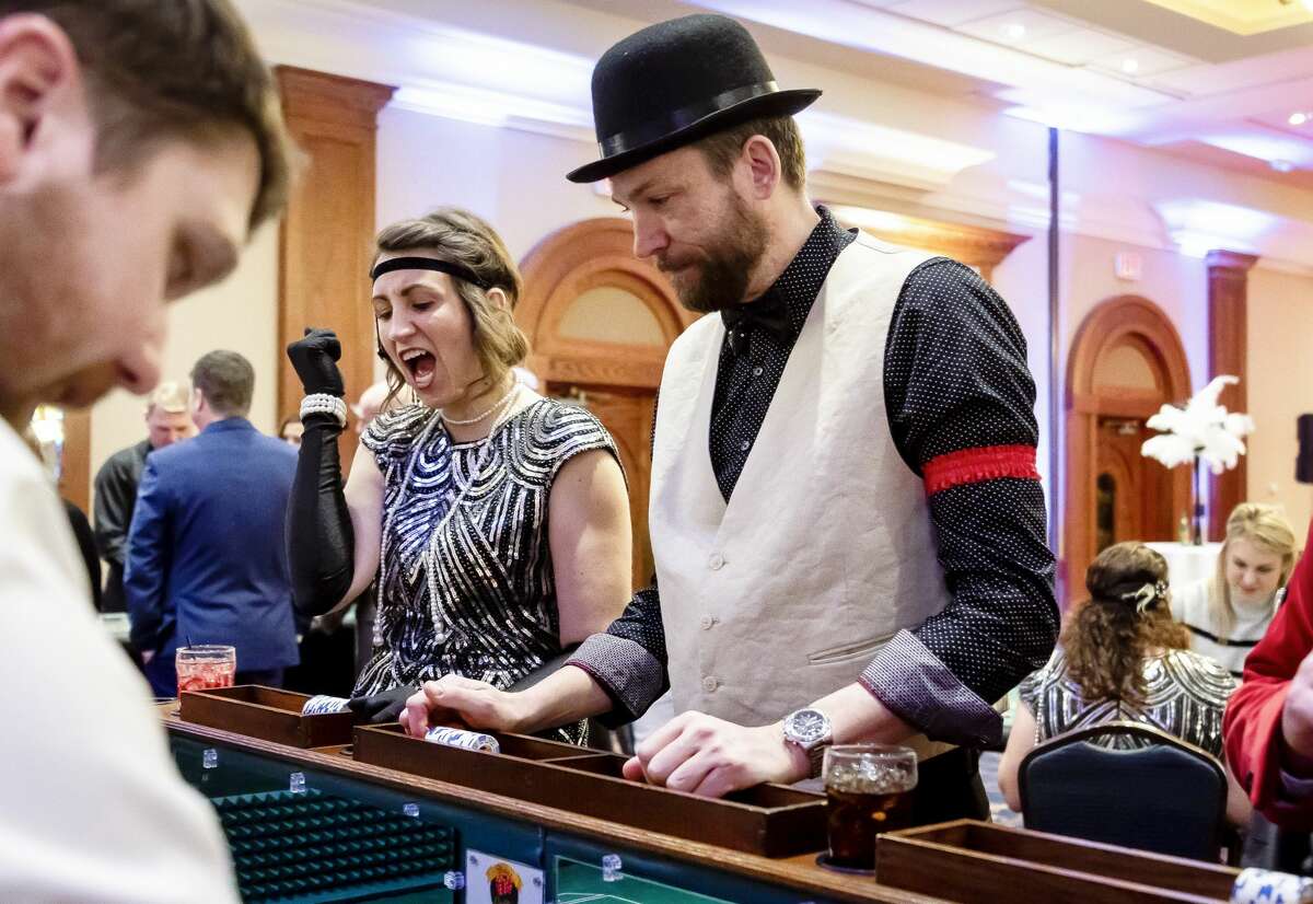 Amanda Welch (left) and Peter Buist (right) play craps during Disability Network of Mid-Michigan's annual fundraiser, Feathers and Fedoras, Saturday, Feb. 15, 2020 at the Great Hall Banquet and Convention Center. (Cody Scanlan/for the Daily News)