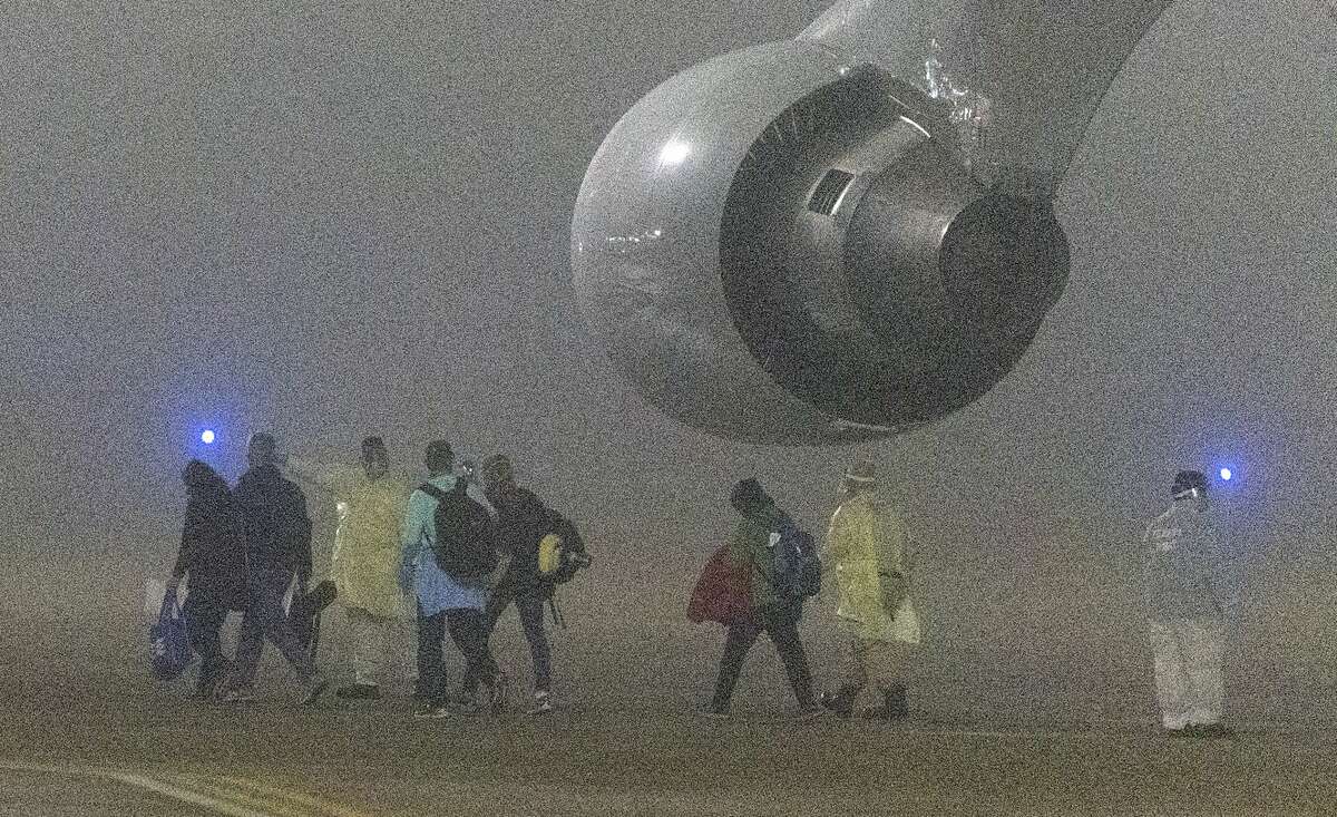 American passengers evacuated from a cruise ship in Japan disembark Monday morning, Feb. 17, 2020 from a Kalitta Air flight at Kelly Field. The passengers had been quarantined on the cruise ship as part of coronavirus control measures.