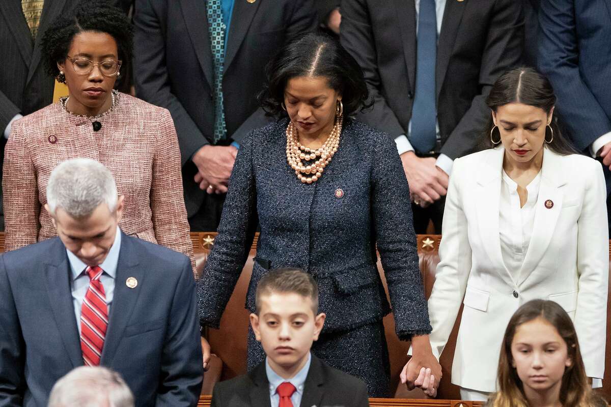 From left in center row, Rep. Lauren Underwood, D-Ill., Rep. Jahana Hayes, D-Conn., and Rep. Alexandria Ocasio-Cortez, D-N.Y, hold hands during an opening prayer as the House of Representatives assembles for the first day of the 116th Congress at the Capitol in Washington, Thursday, Jan. 3, 2019. (AP Photo/J. Scott Applewhite)