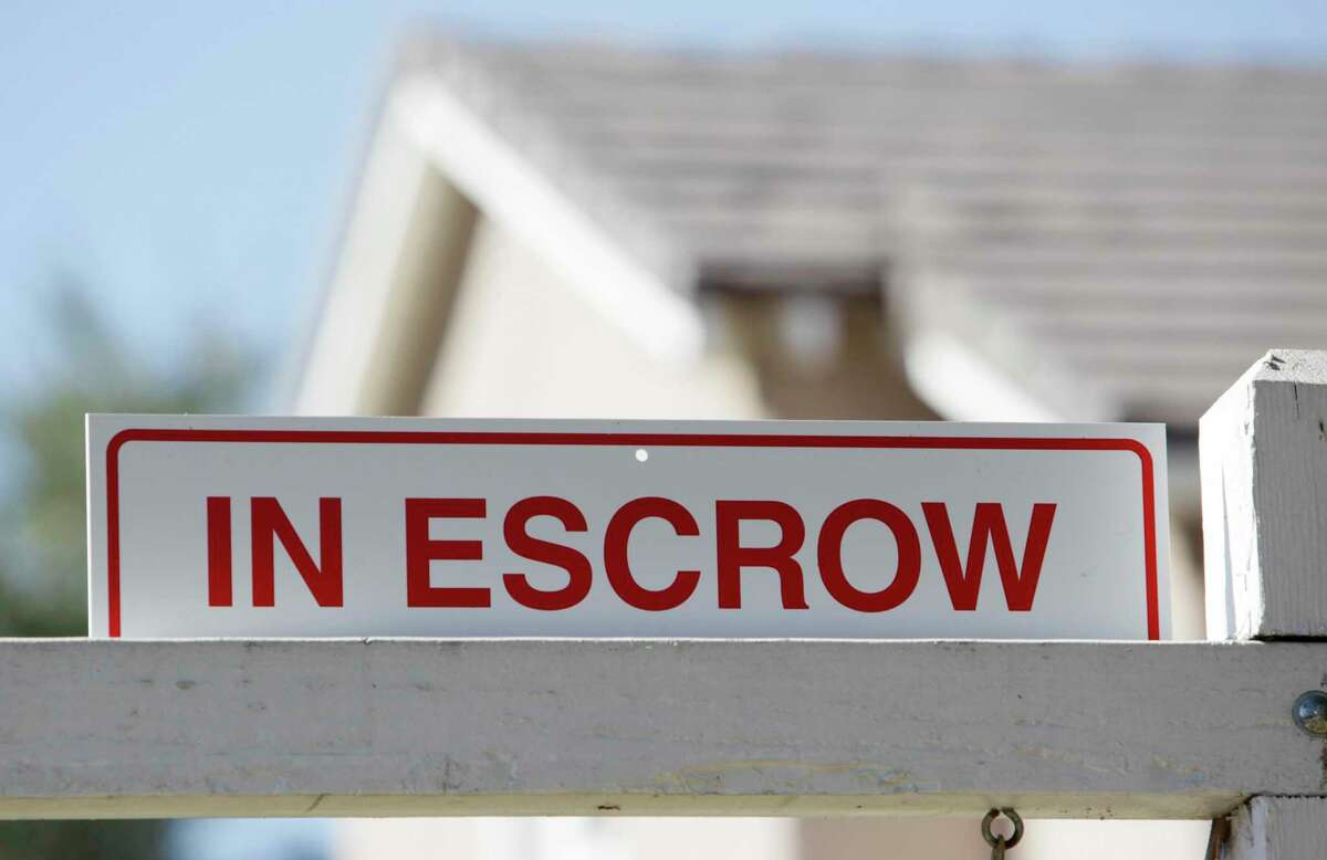 In this photo made Tuesday, Nov. 17, 2009, an 'in escrow' sign has been added to a 'for sale' sign outside a home in Los Angeles. Escrow, the final step to owning your first home, can take well over a month. Here’s what you need to know about completing the closing process.
